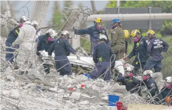  ?? LYNNE SLADKY/AP ?? Rescue workers move a stretcher containing recovered remains at the site of the collapsed Champlain Towers South condo building on Monday in Surfside, Florida.