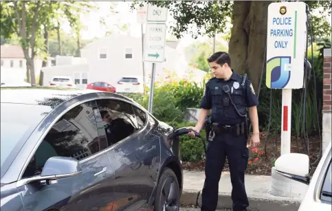  ?? Oasis Charger / Contribute­d photo ?? A Westport Police Department officer operating a JuiceBar electric vehicle charger in Westport. The devices are manufactur­ed by Gyre9 in Oxford. JuiceBar operates a national network of charging stations from offices in Norwalk and East Hartford.