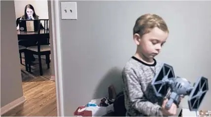  ?? AARON LAVINSKY/STAR TRIBUNE ?? Elena Williams works on some school work as her son, Parker, 4, plays with a Star Wars toy in his room.