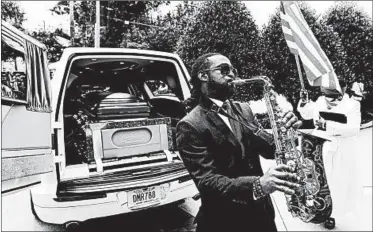  ?? JOHN BAZEMORE/AP ?? A musician plays music behind the hearse carrying the casket of Rayshard Brooks on June 23 in Atlanta.