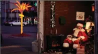  ?? (John Locher/AP) ?? Bill Sandeen, dressed as Santa Claus, waits for cars at a drive-through Santa selfie station at Glittering Lights, a Christmas lights display in Las Vegas, on Dec. 11.