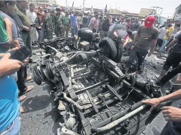  ?? AFP ?? Iraqis check the site of a car bomb attack in Sadr City, a Shia area north of Baghdad, yesterday.