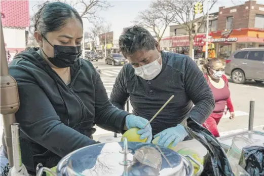  ?? MARSHALL RITZEL/AP ?? Ruth Palacios and Arturo Xelo, a married couple from Mexico, work at their fruit stand in Queens. They worked seven days a week for months, disinfecti­ng COVID-19 patients’ rooms at Memorial Sloan Kettering Cancer Center in New York City but weren’t paid overtime, according to a federal lawsuit they filed against the contractor that hired them. They’re now selling fruit to make ends meet.