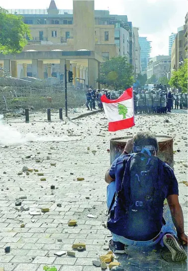  ??  ?? Un manifestan­te con una bandera de Líbano en una de las calles durante los enfrentami­entos con agentes de la policía