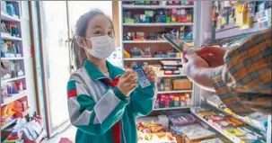  ?? YU DONGHAI / FOR CHINA DAILY ?? A stationery store owner scans the QR code of 8-year-old primary school student Lan Xige as she visits the business in Qiqihar.