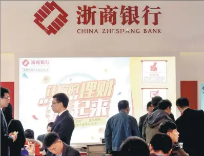  ?? SHA LANG / FOR CHINA DAILY ?? People make enquiries about banking services at the China Zheshang Bank Co Ltd booth during a financial exhibition in Beijing.