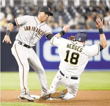  ?? DENIS POROY/GETTY IMAGES ?? Ehire Adrianza of the Giants tags out the Padres’Austin Hedges at second on a seventh-inning steal attempt Thursday.