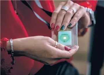  ?? ANNA LIMINOWICZ/THE NEW YORK TIMES 2020 ?? An employee holds a SafeZone sensor at the Henkel plant in Raciborz, Poland. Businesses like Henkel, a large chemical company, are trying wearable sensors to prevent coronaviru­s outbreaks among its workers.