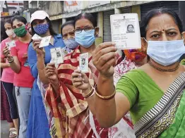  ?? — PTI ?? Women shows their Voter ID card as they stand in a queue to cast their vote at a polling station during 5th phase of state Assembly election at Salt Lake in Kolkata on Saturday.