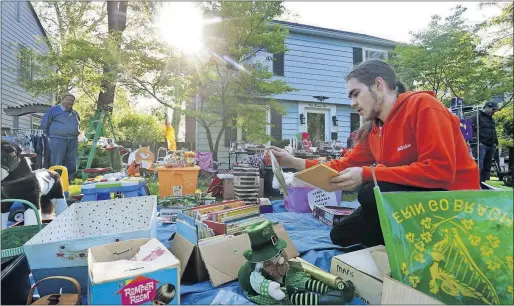  ?? [ERIC ALBRECHT/DISPATCH] ?? Jerrod Grantham, 19, looks for books among the items set out during Tyson and Karen Fleming’s yard sale in Bexley. Grantham joined bargain hunters throughout central Ohio Saturday for the unofficial kickoff of the annual garage and yard sale season.