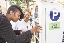  ?? Brett Coomer / Houston Chronicle ?? Tyra Brown uses one of the city’s new parking meters Tuesday as Olga Valdez, a parking compliance officer, stands by in downtown.