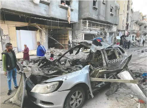  ?? AFP VIA GETTY IMAGES ?? Onlookers check the car in which three sons of Hamas leader Ismail Haniyeh were reportedly killed on Wednesday.