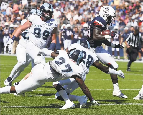  ?? Jessica Hill / Associated Press ?? UConn running back Kevin Mensah runs past Rhode Island defensive lineman Brandon Ginnetti ( 99), linebacker Nas Jones ( 27), and defensive back Momodou Mbye ( 28) for a touchdown on Saturday.