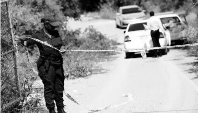  ?? RICARDO MAKYN/CHIEF PHOTO EDITOR ?? A policewoma­n cordons off the entrance to the now-defunct fishing village off the Portmore toll road in St Catherine, where the body of an unidentifi­ed woman was discovered yesterday. The parish of St Catherine, which has been under a state of emergency since September 5, recorded 183 murders up to November 9 this year, 15 more than in 2018.