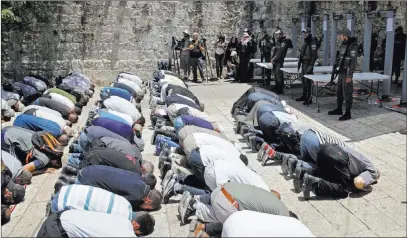  ?? Mahmoud Illean ?? The Associated Press Israeli border police officers stand guard as Muslim men pray Sunday outside the Al Aqsa Mosque compound in Jerusalem.