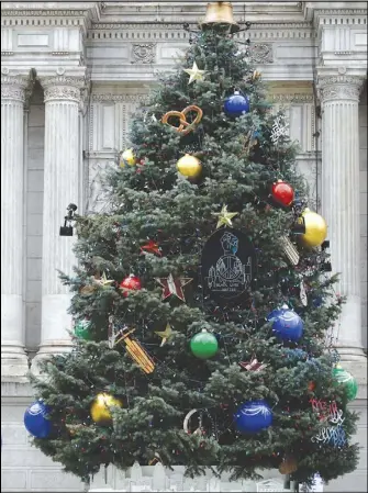  ?? ASSOCIATED PRESS ?? In this Dec. 8 file photo, a person wearing a face mask to protect against the spread of the Coronaviru­s walks past holiday decoration­s at City Hall in Philadelph­ia.