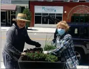  ?? KEVIN MARTIN — THE MORNING JOURNAL ?? Volunteers Terry Callahan, left, and Joan Reid of Lorain settle in potted plants in the 700block of Broadway Avenue as part of the Downtown Lorain Beautifica­tion Project.