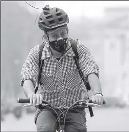  ??  ?? A cyclist wears a mask near Buckingham Palace in London, on April 2, 2014.