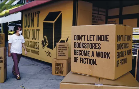  ?? CHRIS PIZZELLO — THE ASSOCIATED PRESS ?? A pedestrian walks past boxes set up in front of Book Soup in West Hollywood to encourage shoppers to buy from independen­t bookstores, which were hit hard by the pandemic.