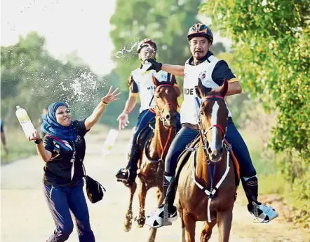  ??  ?? Going for gold: Sultan Mizan (front) getting a bottle of water at a refreshmen­t stop during the 80km equestrian endurance race at the Terengganu Internatio­nal Endurance Park in Lembah Bidong.