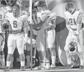  ?? Kin Man Hui / San Antonio Express News ?? Floresvill­e’s Salih Williams, from left, Nathan Pollok and Kane Numera bow in prayer before their District 29-5A title game against Southside on Friday night in Floresvill­e.