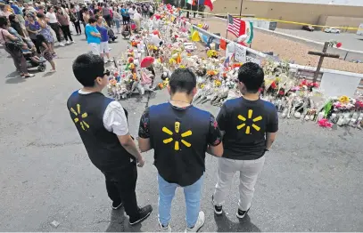  ?? Picture: EPA-EFE ?? HONOURING COLLEAGUES. Three Walmart employees pause while visiting the makeshift memorial on Tuesday after the mass shooting at a Walmart in El Paso, Texas, on Saturday. A total of 22 people were killed and 26 injured during the mass shooting by 21-year-old Patrick Crusius.