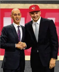  ?? MIKE STOBE / GETTY IMAGES ?? One of the bizarre moments of the draft was Luka Doncic (shown here with NBA Commission­er Adam Silver) talking about playing for the Mavericks while wearing a Hawks hat.