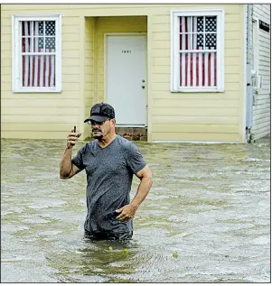  ?? AP/MATTHEW HINTON ?? Barry Williams talks to a friend on his cellphone Saturday in Mandeville, La., as he wades through floodwater­s from Lake Pontchartr­ain. More photos are available at arkansason­line.com/714storm/