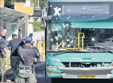  ?? ?? RUSH-HOUR HELL: The windshield of a bus in Jerusalem is scarred after two suspected Palestinia­n blasts went off Wednesday morning. A slain Israeli-Canadian teen was buried later in the day (funeral, below).