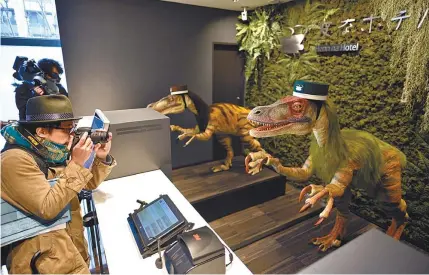  ?? EPA-Yonhap ?? A media member takes pictures of a receptioni­st dinosaur robot during a press preview at a hotel called “Henn na Hotel” in Urayasu, east of Tokyo, Wednesday. Located near Tokyo Disney Resort, the Henn na Hotel Maihama Tokyo Bay features 100 rooms and...