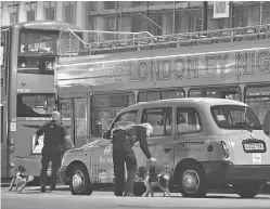  ??  ?? Police sniffer dogs examine vehicles on London Bridge after an incident Saturday. Witnesses described a rampage that left a trail of bloodied bodies on the bridge and in the adjacent Borough Market — both London landmarks.