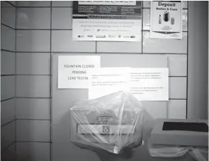  ?? Beth Nakamura/The Oregonian via AP, File ?? ■ A water fountain is covered because of lead in the drinking water May 31, 2016, at Creston Elementary School in Portland, Ore. About 50,000 students in Michigan’s largest district will start the school year today in Detroit by drinking from water coolers after the discovery of elevated levels of lead or copper. Detroit isn’t the first major school district to switch to bottled water. The 49,000-student district in Portland turned off fixtures in 2016 after a lead scandal.