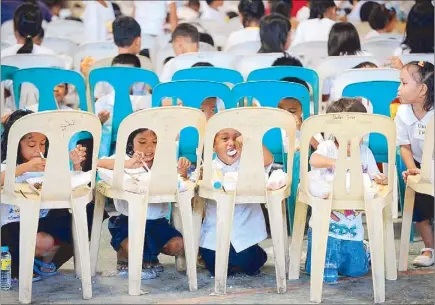  ?? AFP ?? Preschool and elementary students eat packaged meals during a feeding program at a slum area in Manila yesterday. The city government distribute­d food to the children as part of the celebratio­n of Manila’s 441st anniversar­y.