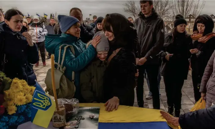  ?? Roman Pilipey/AFP/Getty Images ?? Lilia (centre right) and nine-year-old Matviy (centre), the wife and son of Andriy Katanenko, 39, who was killed in action near Avdiivka, mourn next to his coffin during a funeral ceremony in Bucha, north-west of Kyiv. Photograph: