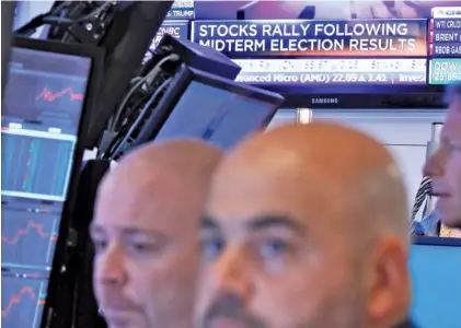  ?? AP PHOTO/RICHARD DREW ?? Traders work in a booth Wednesday on the floor of the New York Stock Exchange. Technology and health care stocks led indexes broadly higher on Wall Street as results of the midterm elections came in largely as investors had expected.