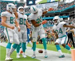  ??  ?? Los jugadores de Miami celebran tras el touchdown de Kenyan Drake (32) ante Lions.