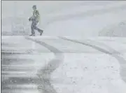  ?? AP ?? A pedestrian walks across the Highway 38 overpass above I-15 in the California Cajon Pass amid heavy snowfall.
