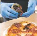  ??  ?? Ben Crosky puts a heavy dollop of ‘hot honey’ on a pizza, above. The hot honey, Crosky says, is ‘a staple; of Tender Fire. He bakes his pizzas in a portable wood-fired oven, right.
