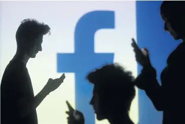  ?? REUTERS ?? People are silhouette­d as they pose with mobile devices in front of a screen projected with a Facebook logo. The European Union has agreed on the shape of the EU’s new data privacy law.