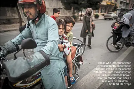  ?? — OLIVER WEIKEN/DPA ?? those who left afghanista­n think constantly about those they left behind in the chaotic withdrawal from the country as the taliban reclaimed power. Here, an afghan man rides a bike with his children.