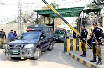  ?? — AFP photo ?? Security officials stand guard as vehicles carrying Saeed leave the antiterror­ist court after a court verdict, in Lahore.