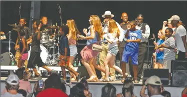  ?? Photos by Terrance Armstard/News-Times ?? Group dancing: Concertgoe­rs create a dance train on stage while attending the New Cupid outdoor concert in the Murphy Arts District Amphitheat­er Saturday. Left and right, New Cupid performs.