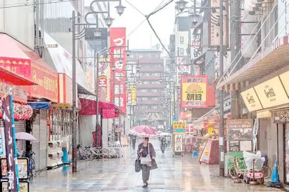  ?? PHILIP FONG/AGENCE FRANCE-PRESSE ?? WORKERS walk along Shinsekai shopping street in Osaka as record numbers of new Covid-19 infections were reported in the city in recent days.