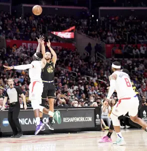  ?? — AFP photo ?? Stephen Curry (centre) of the Golden State Warriors shoots and scores a threepoint basket against Reggie Jackson (left) of the Los Angeles Clippers during the second half at Staples Centre in Los Angeles, California.