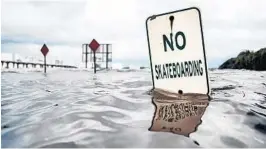  ??  ?? In Jacksonvil­le, in northern Florida, a “No Skateboard­ing” sign is almost completely engulfed by the rising water during a rainstorm.