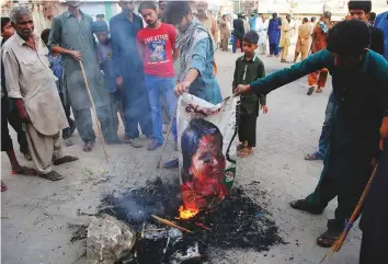  ?? AP ?? Protesters burn a poster with the image of Asia Bibi, acquitted of blasphemy charges after eight years on death row, in Hyderabad last Thursday.