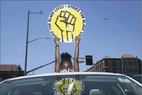 ?? JAE C. HONG — THE ASSOCIATED PRESS FILE ?? In this July 20, 2020, file photo, Audrey Reed, 8, holds up a sing through the sunroof of a car during a rally in Los Angeles. Ahead of Labor Day, major U.S. labor unions say they are considerin­g work stoppages in support of the Black Lives Matter movement.