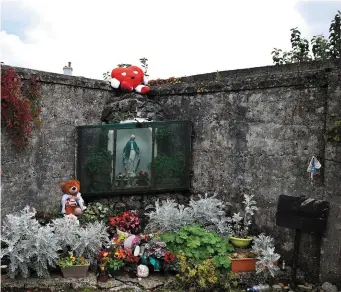  ??  ?? Flowers left at the Virgin Mary shrine at the Tuam Mother and Baby home mass burial site on August 25, 2019 in Tuam, Ireland. Nearly 800 babies and young children who died in the Tuam Home run by the Bon Secours order of nuns for unmarried mothers are buried there.