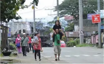  ?? — AFP ?? MINDANAO: A resident carries a relative as they evacuate from their homes in Marawi, in southern island of Mindanao yesterday, after government planes and helicopter­s bombed Islamic militants position. Philippine security forces dropped more bombs on a...