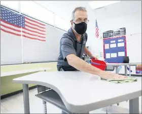  ?? CHARLIE NEIBERGALL — THE ASSOCIATED PRESS FILE ?? Custodian Doug Blackmer cleans a desk in a classroom at the Jesse Franklin Taylor Education Center in Des Moines, Iowa.